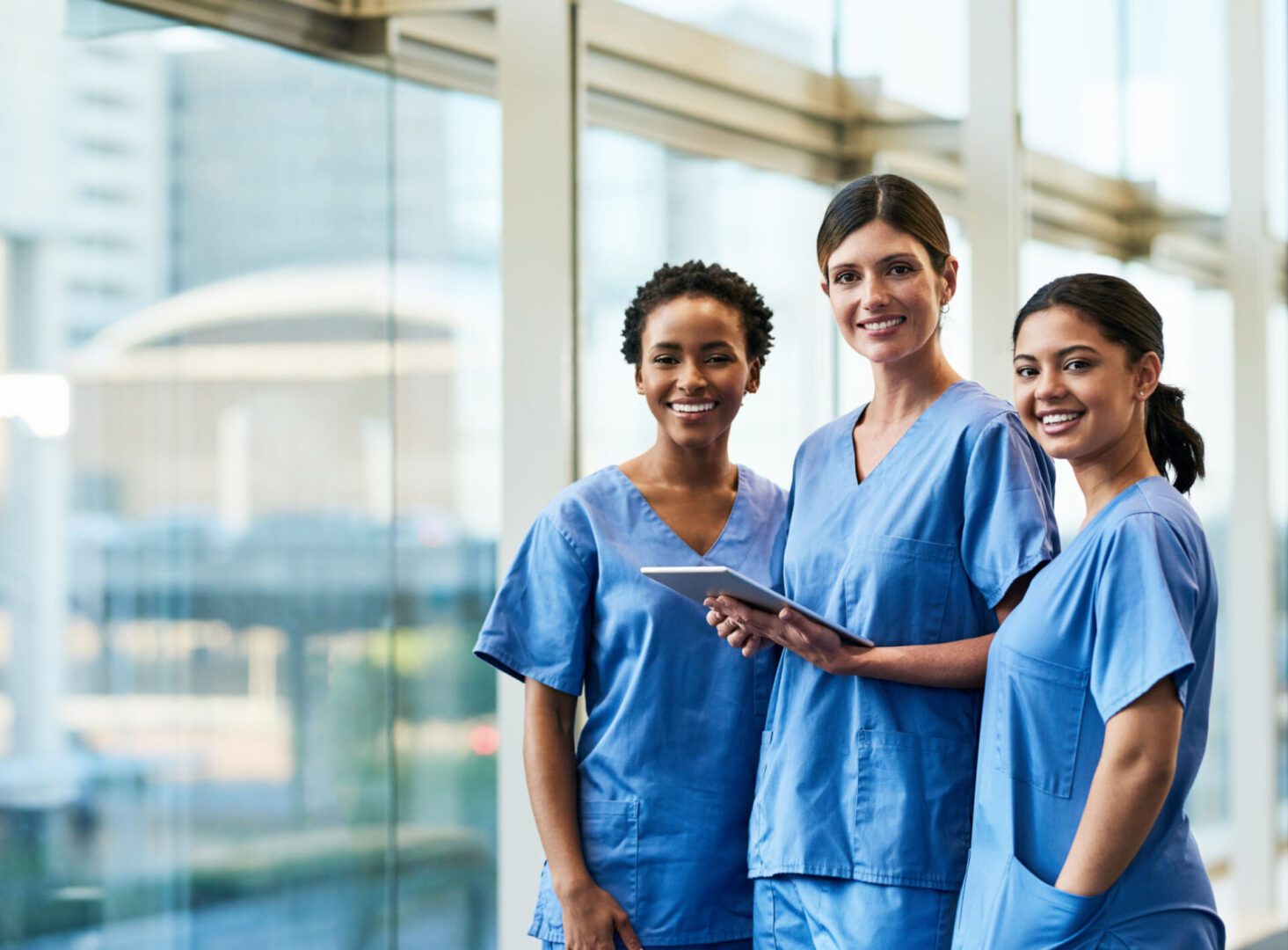 Healthcare professionals in blue scrubs smiling together.