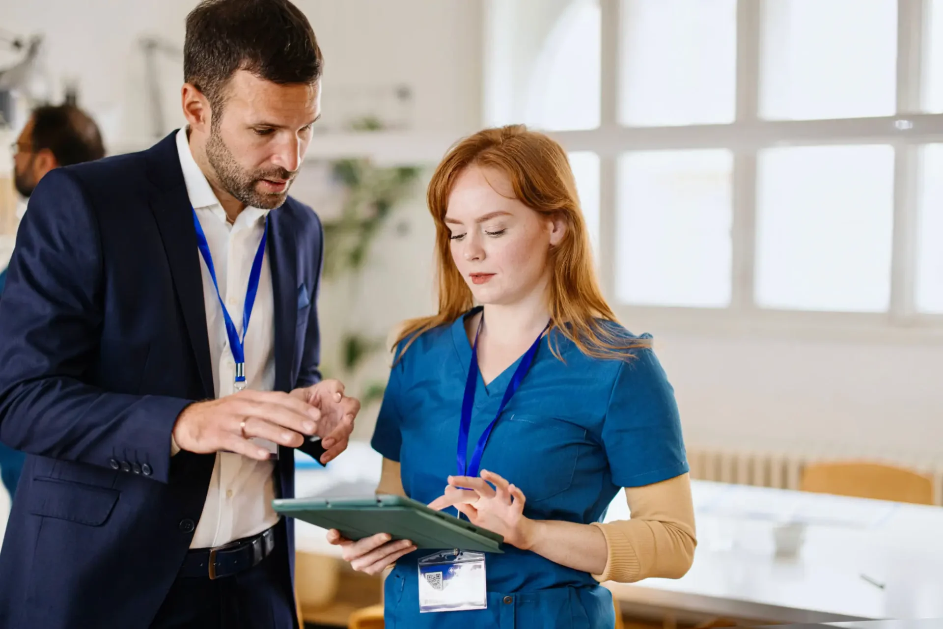 Two professionals discussing work with a clipboard in a bright office.