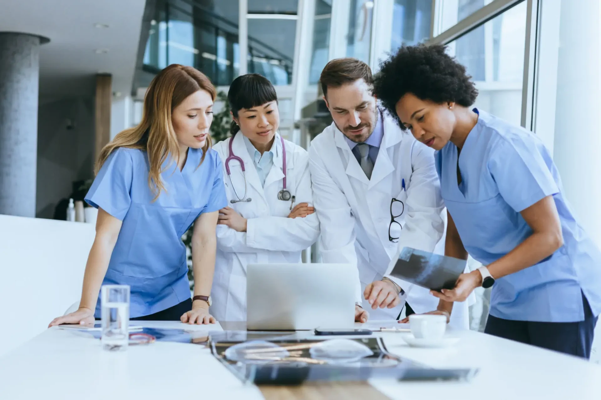 Medical team collaborating on patient data using a laptop.