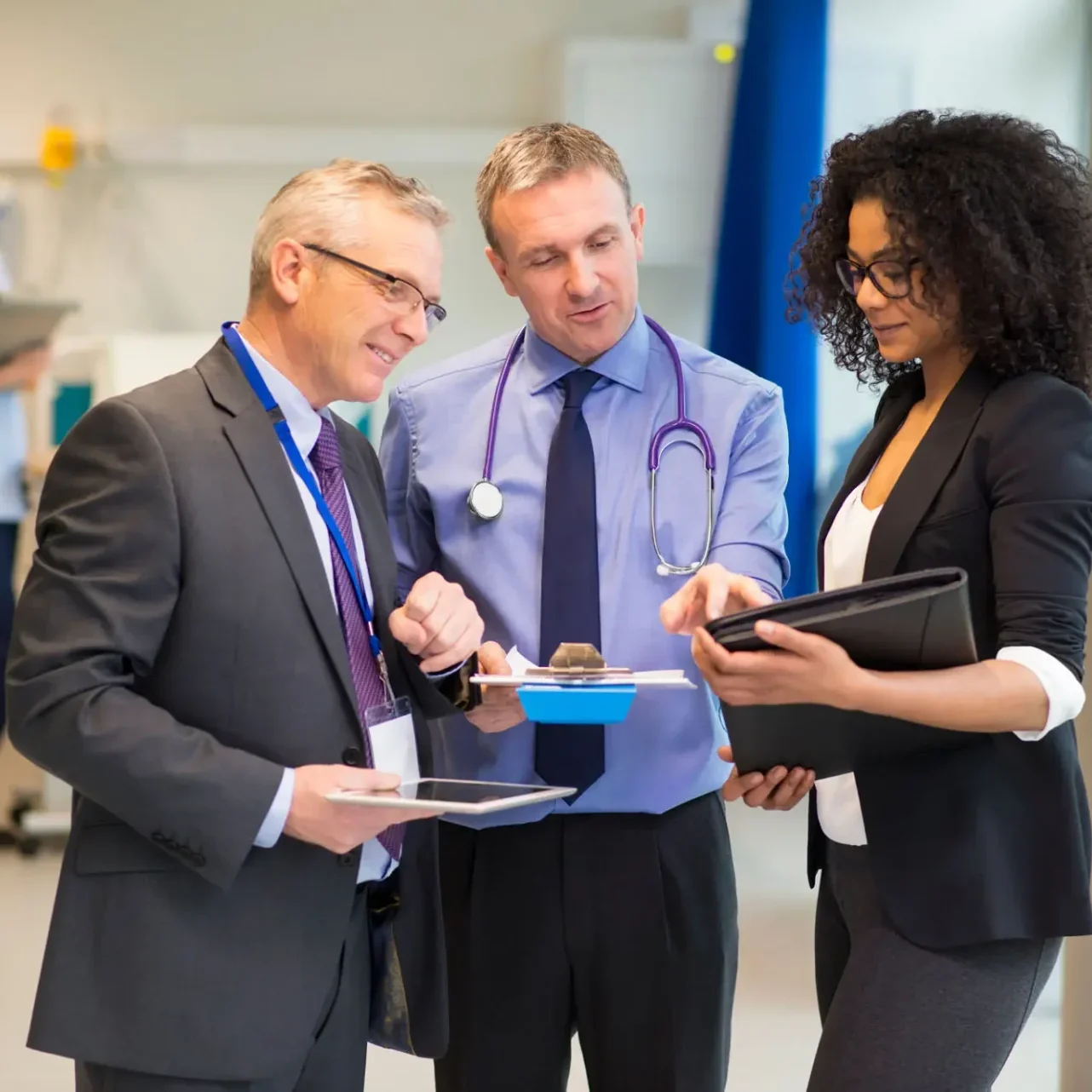 Three professionals discussing documents in an office setting.